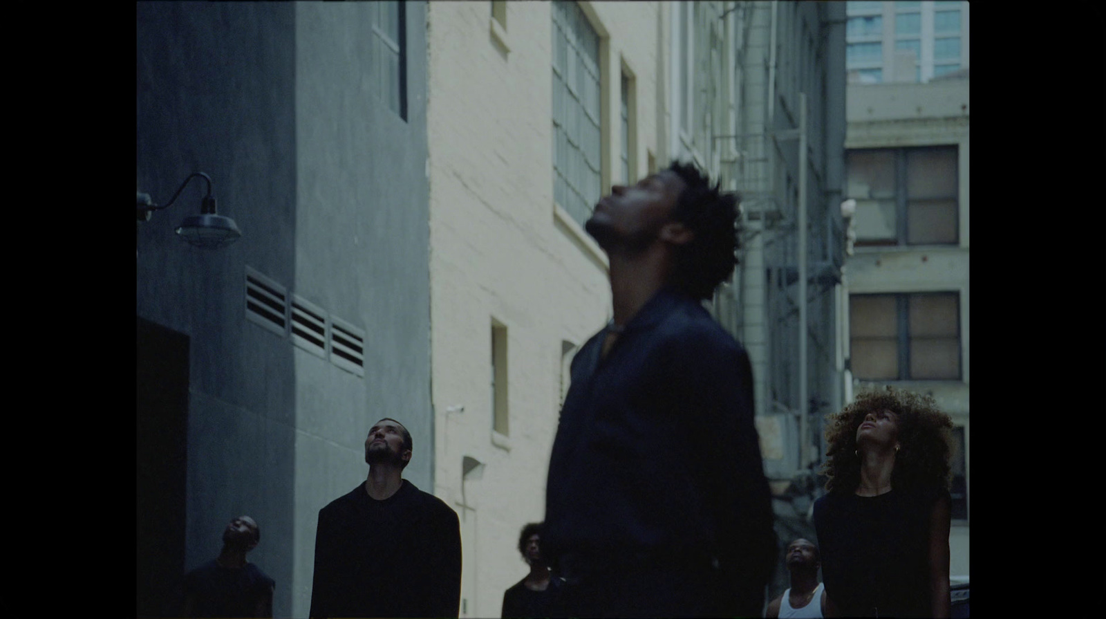 a group of people walking down a street next to tall buildings