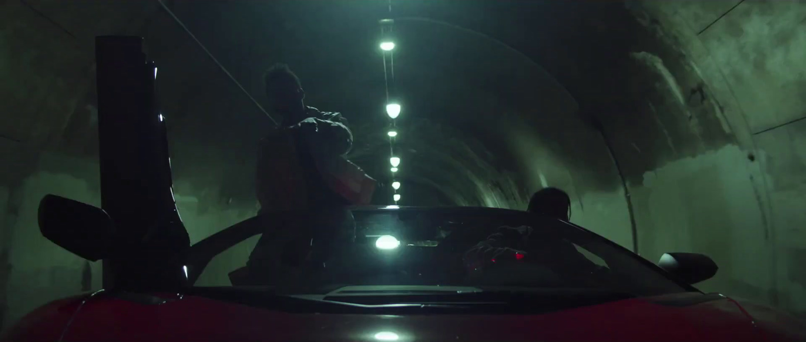 a man standing on top of a car in a tunnel