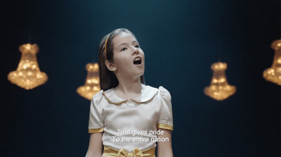 a young girl standing in front of a chandelier