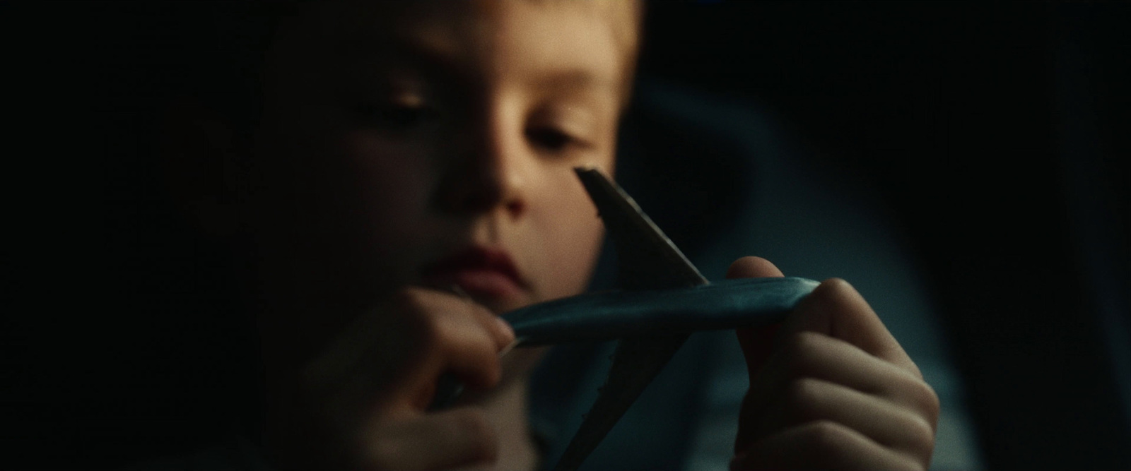 a young boy holding a pair of scissors in his hand