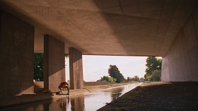 a man sitting on the side of a road next to a river