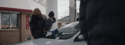 a couple of people standing next to a white car