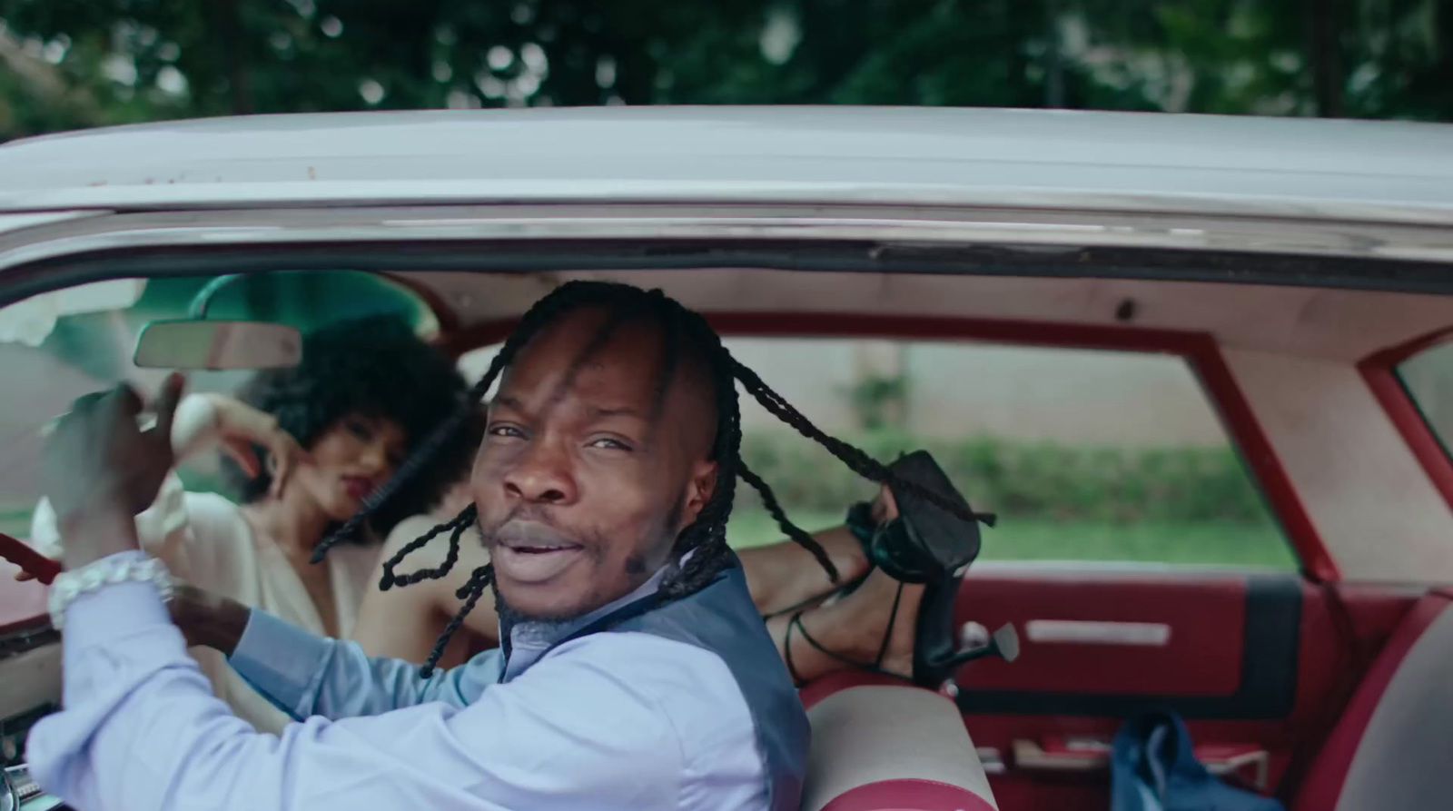 a man sitting in a car with dreadlocks on