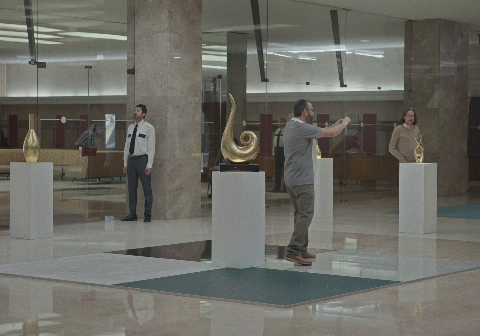 a man standing in a lobby next to a statue