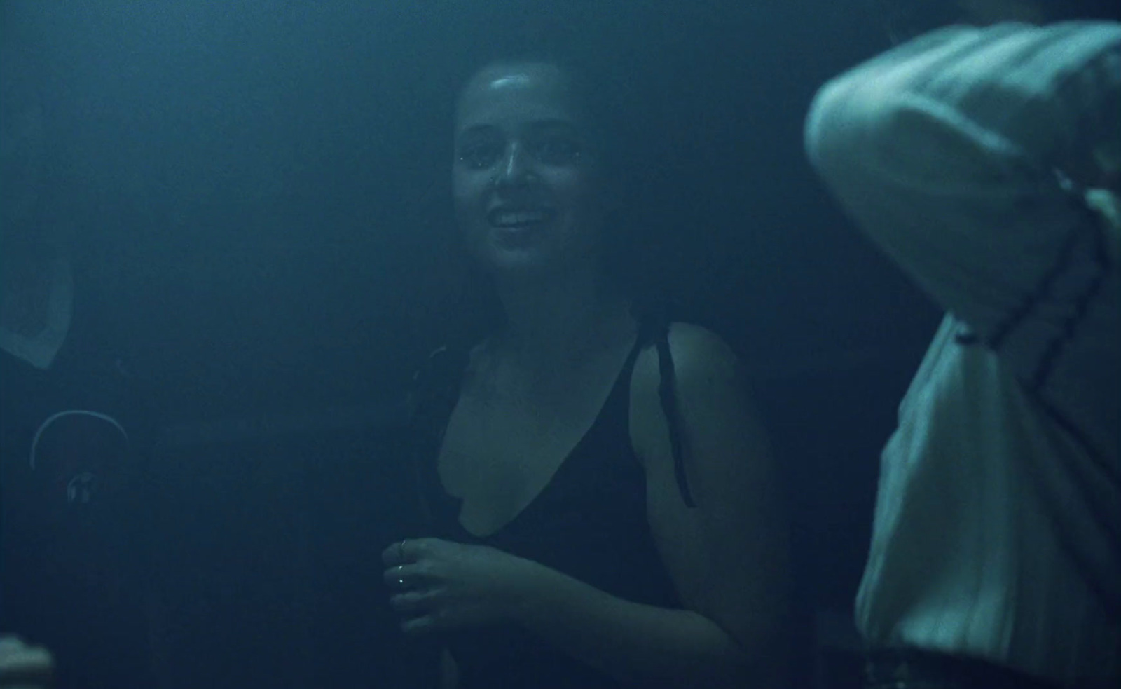 a woman standing in a dark room next to a man