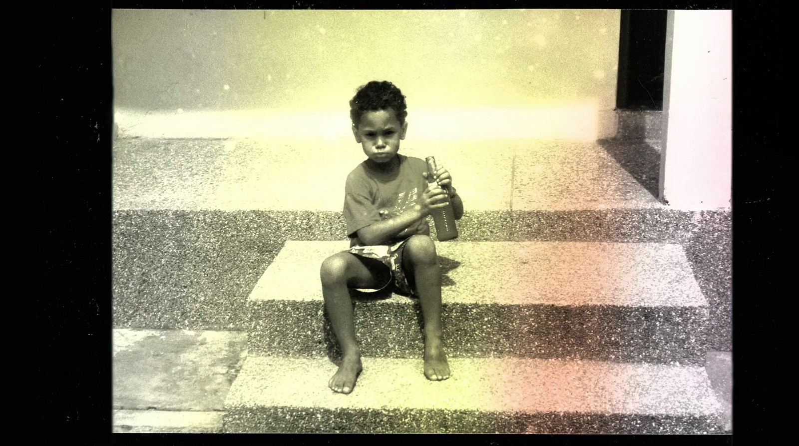 a little girl sitting on a chair holding a bottle