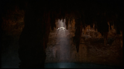 a cave with a waterfall and a light at the end