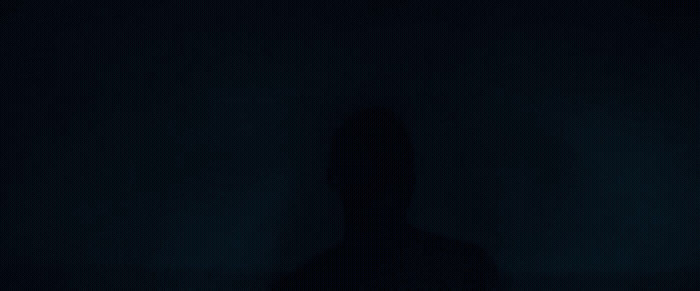 a person standing in the dark with their shadow on the wall