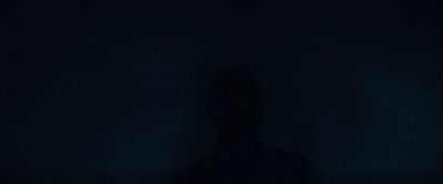 a person standing in the dark with their shadow on the wall