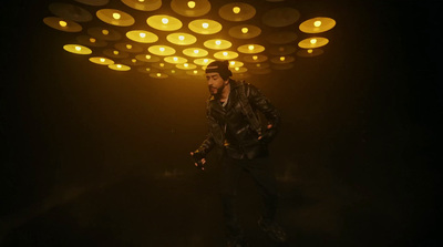 a man in a leather jacket standing in a dark room