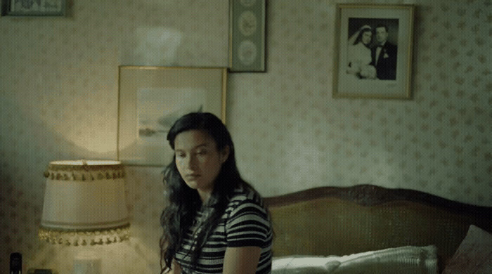 a woman standing in a bedroom next to a bed