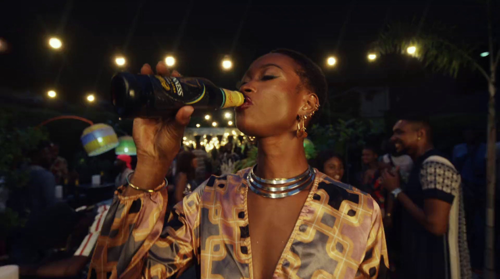 a woman drinking from a bottle while standing in front of a crowd