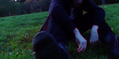 a person sitting in the grass with their hands on their knees