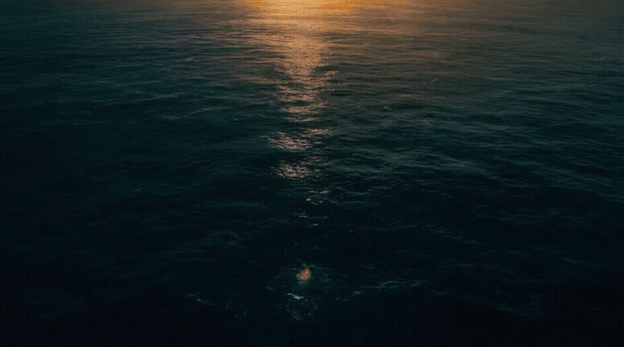 a large body of water with the sun in the distance