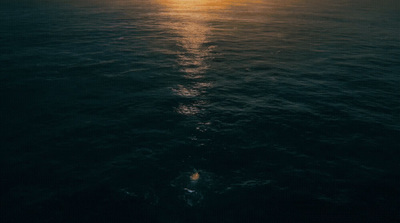 a large body of water with the sun in the distance