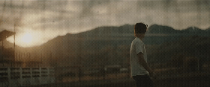 a man standing in front of a fence at sunset