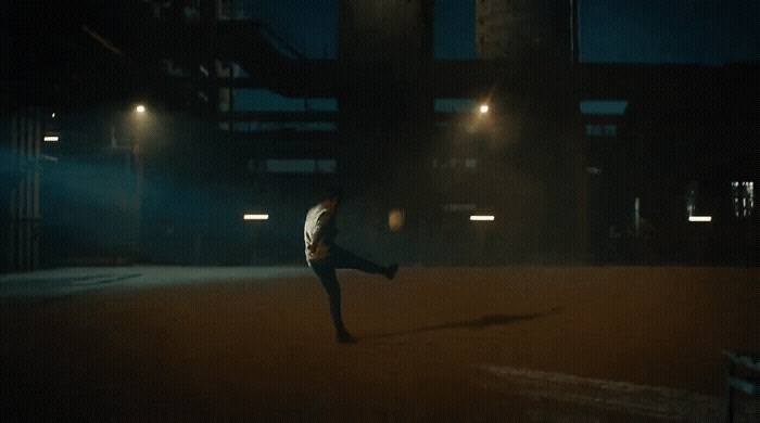 a man is kicking a soccer ball in the dark