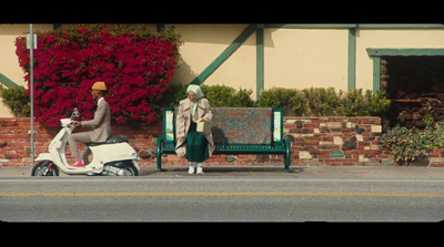 a man and woman sitting on a bench next to a scooter