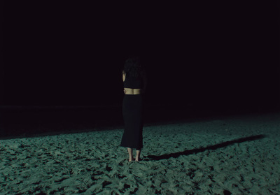 a woman standing in the sand at night