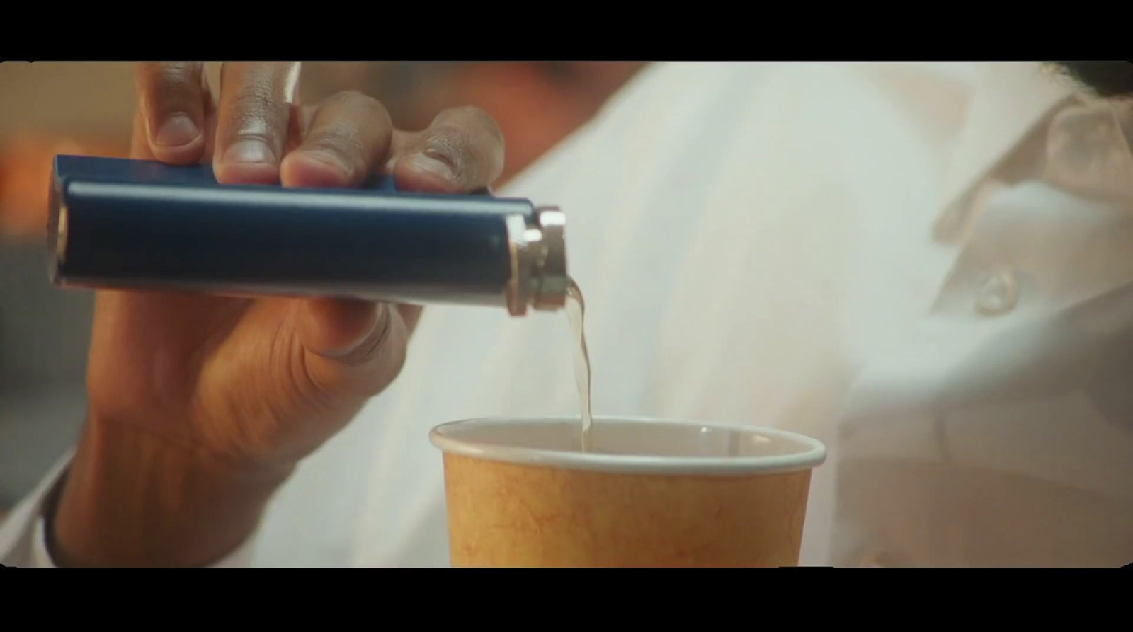 a person is pouring something into a cup