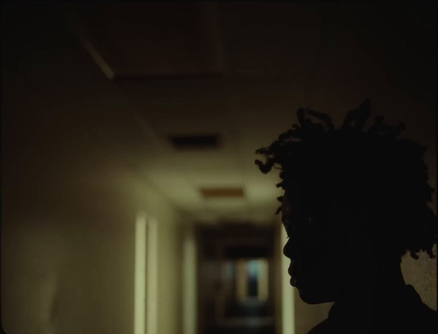 a person with dreadlocks standing in a hallway