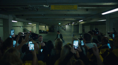 a group of people holding up cell phones in a parking garage