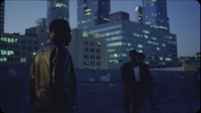 two men standing in front of a city skyline at night