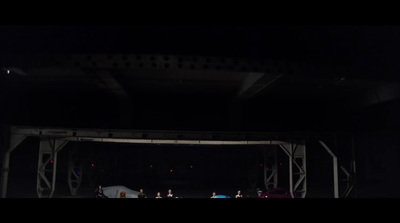 a group of people standing under a bridge at night