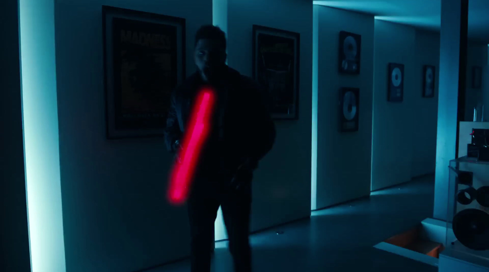 a man standing in a hallway holding a red light saber