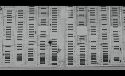 a black and white photo of a person climbing up the side of a building