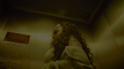 a man with long hair standing in a bathroom