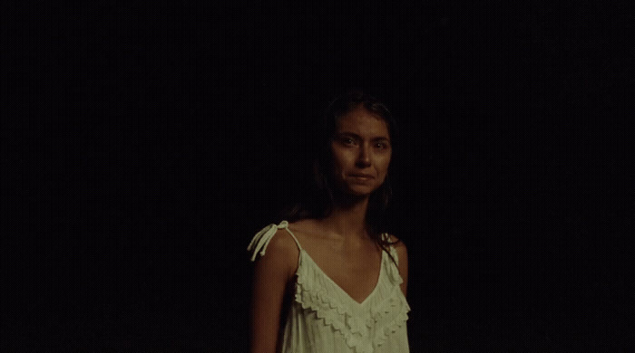 a woman in a white dress standing in the dark