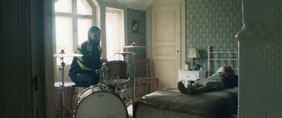 a man sitting on a bed next to a drum set