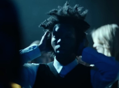 a man with dreadlocks standing in front of a group of people