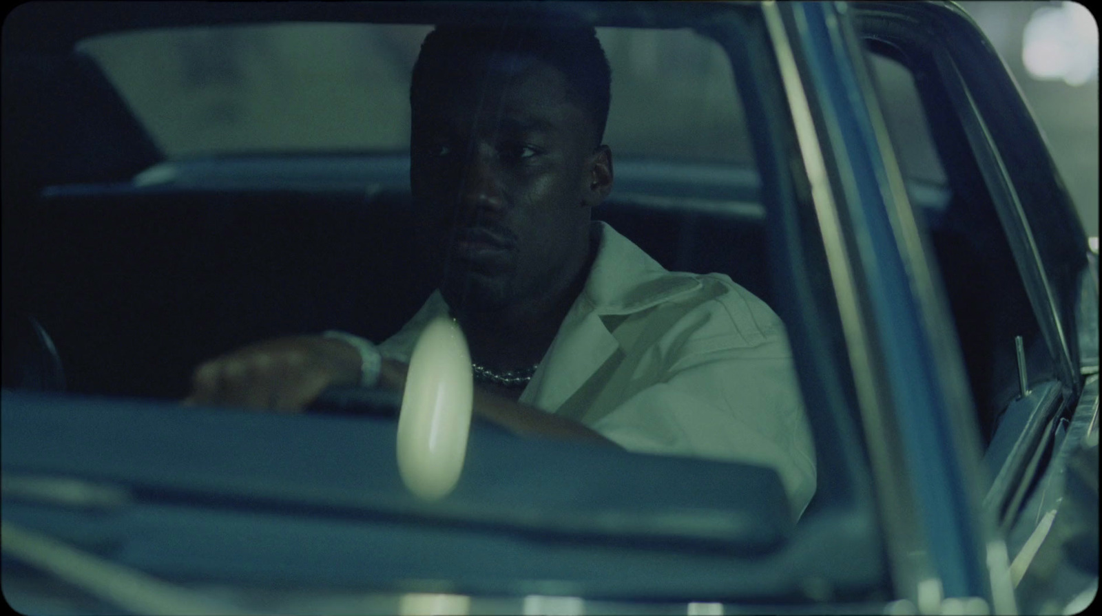 a man sitting in a car with his hand on the steering wheel