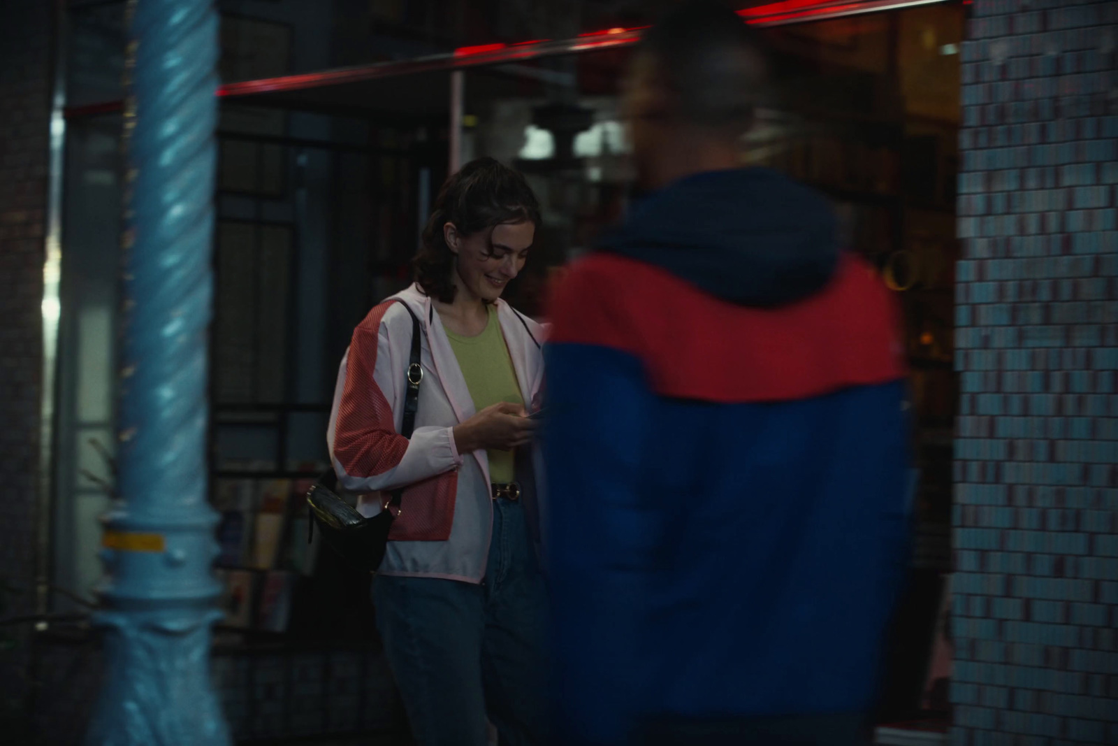 a woman standing in front of a building looking at her cell phone