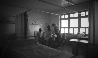 a group of people standing around a hospital bed