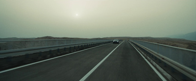 a car driving on a highway with mountains in the background