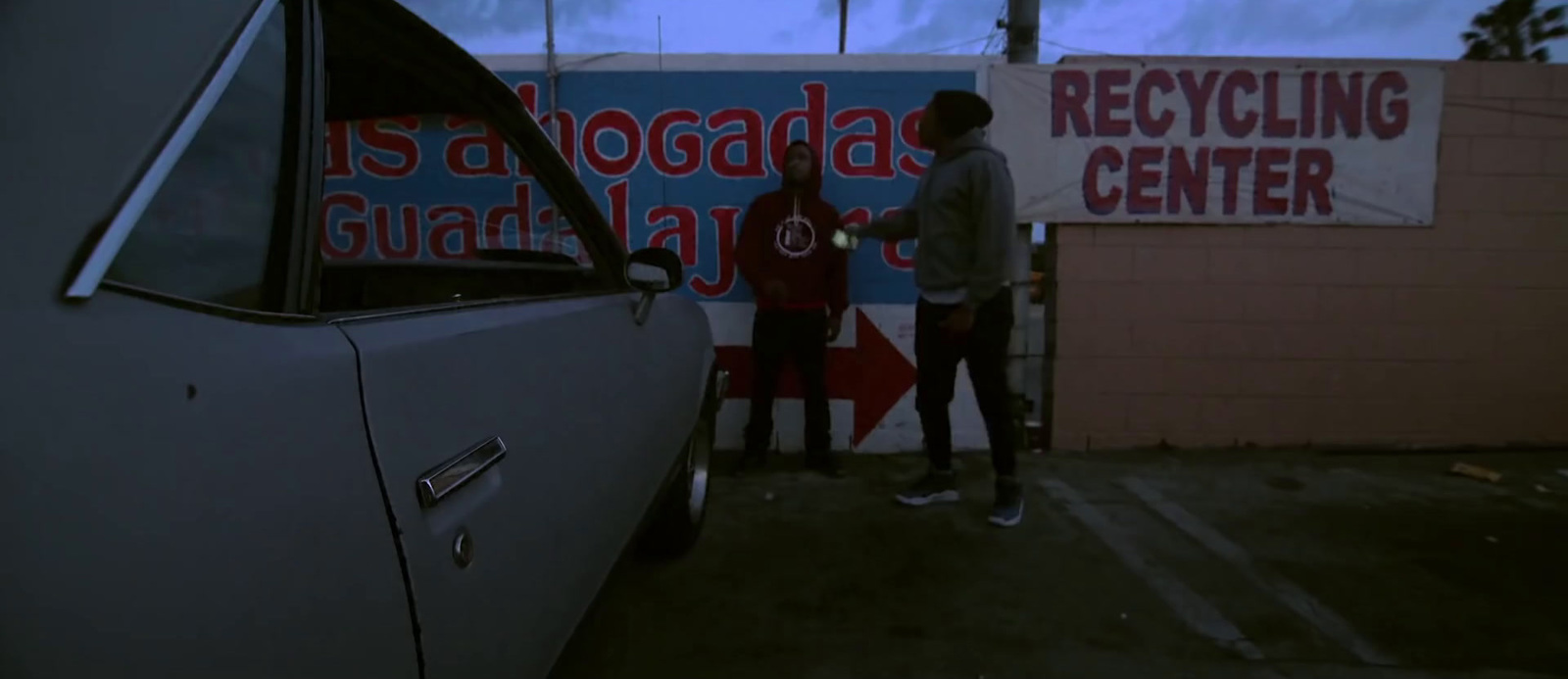 a couple of people standing next to a parked car