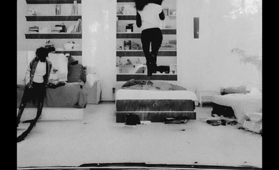 a black and white photo of a person jumping on a bed