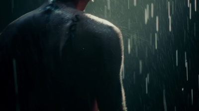 a man standing in the rain with his back to the camera