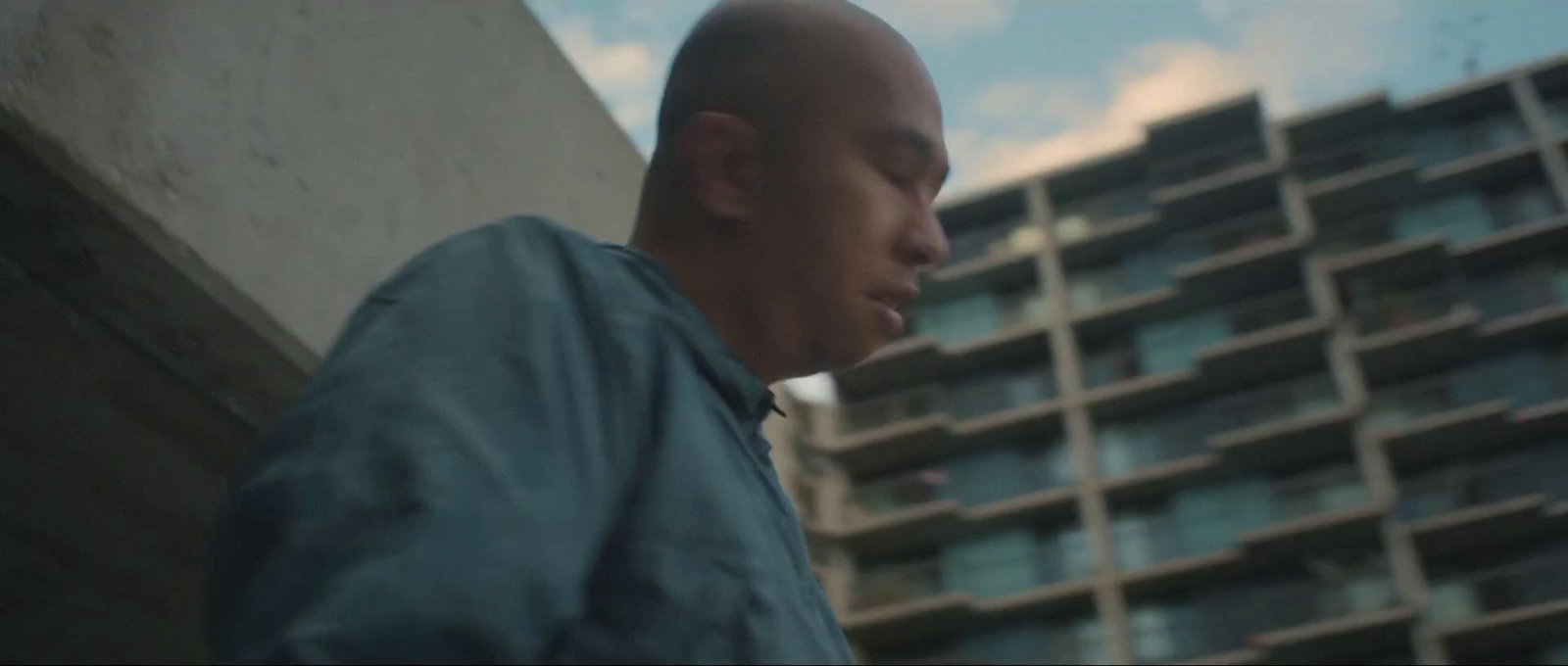 a bald man standing in front of a tall building