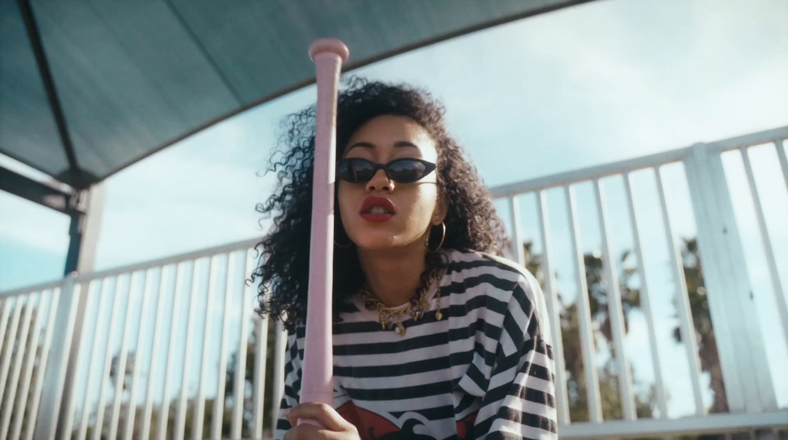 a woman in a striped shirt holding a pink bat