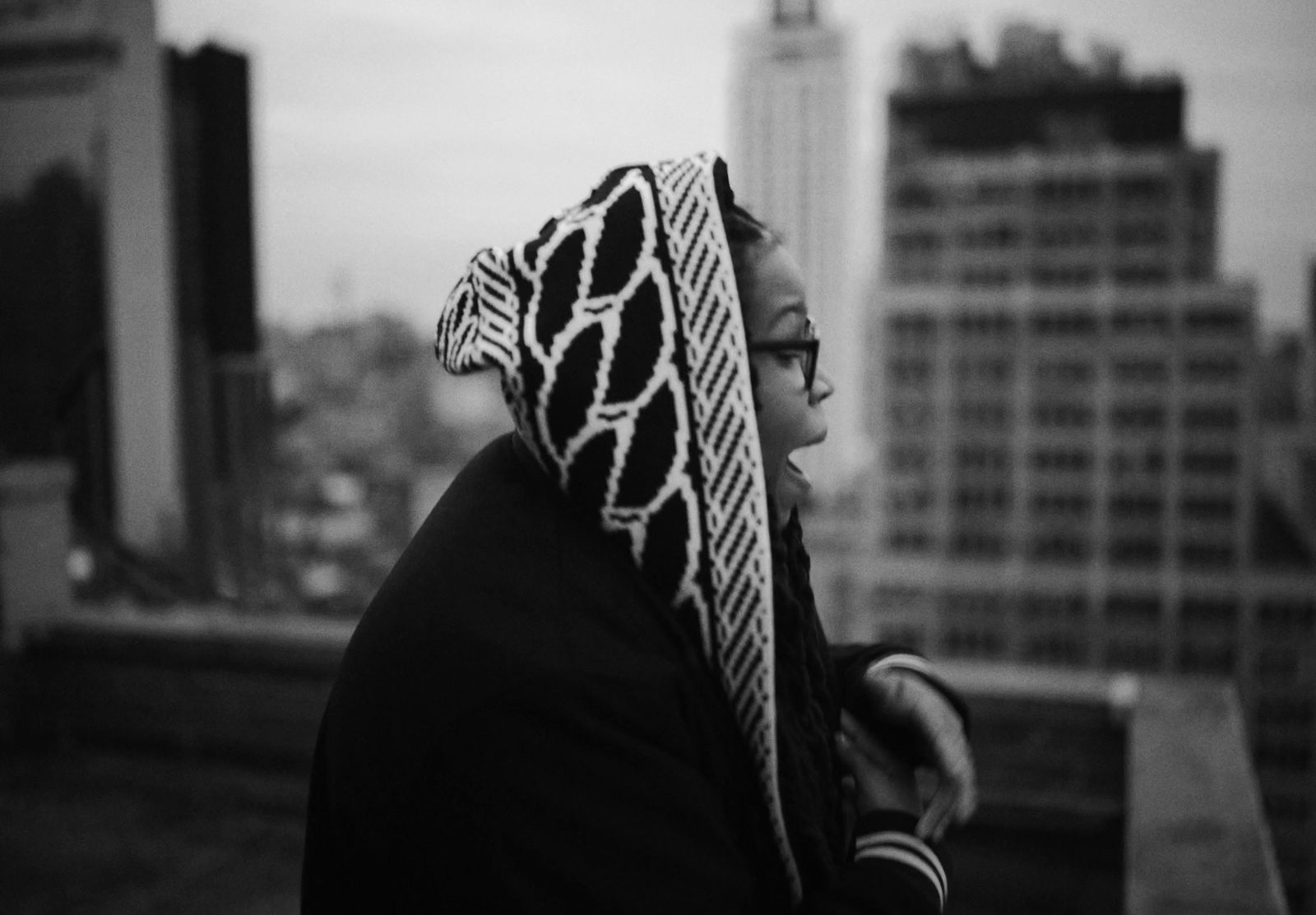 a woman with a scarf on her head looking out over a city