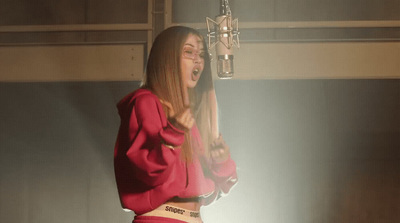 a woman in a red top is singing into a microphone