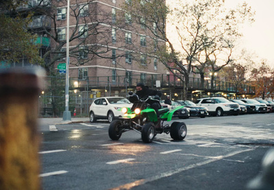 a man riding a green four wheeler on a city street