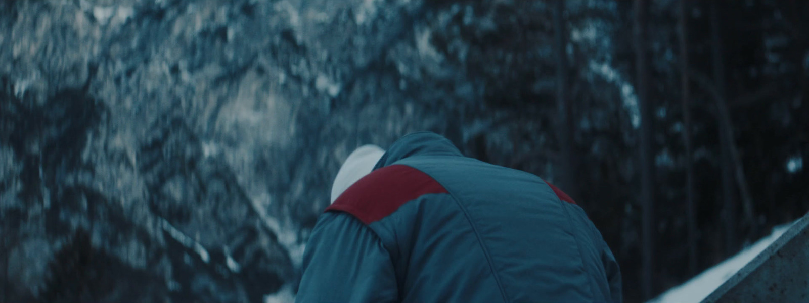 a man in a blue jacket is walking in the snow