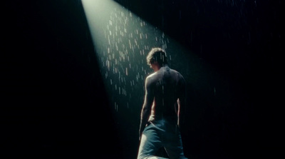 a man standing in the rain under a spotlight