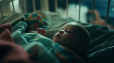 a baby laying in a crib with a blanket