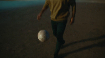 a man in a yellow shirt is kicking a soccer ball